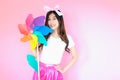 Portrait beautiful asia teen girl beaming smile on pink background, fashion summer set with colorful wind turbine or pinwheel or w