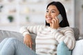 Portrait Of Beautiful Asian Female Talking On Mobile Phone At Home