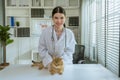 portrait of a beautiful asian female veterinarian with cat on diagnosis table at clinic