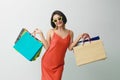 Portrait of beautiful asian girl wearing dress and sunglasses holding shopping bags isolated over blue background Royalty Free Stock Photo