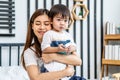 Portrait of a beautiful asian mother with her cute little son with pleasure spending time together, Young mom hugging on a back Royalty Free Stock Photo