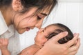 Portrait of beautiful asian mother holding her infant baby boy on hands and kiss with nose Royalty Free Stock Photo