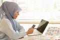 Portrait of beautiful asian muslim woman designer with hijab holding a mockup fake credit card with computer laptop  in her home Royalty Free Stock Photo