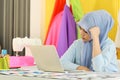 Portrait of beautiful asian muslim woman designer with hijab holding and using computer laptop in her home working studio room Royalty Free Stock Photo