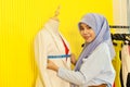 Portrait of beautiful asian muslim woman designer with hijab working with measure tape and model in her studio room Royalty Free Stock Photo