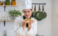 Portrait beautiful Asian professional female chef wearing white uniform, hat, showing plate of spaghetti, cooking in kitchen, Royalty Free Stock Photo
