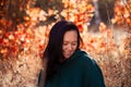 Portrait of a beautiful Asian smiling young woman looking down in an autumn forest on a background of red leaves Royalty Free Stock Photo