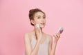 Portrait of beautiful asian woman applying powder puff at cheek makeup of cosmetic isolated over pink background Royalty Free Stock Photo