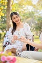 Portrait of beautiful Asian woman having a nice conversation, sipping wine with her friend in the park