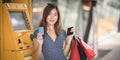 Portrait of beautiful asian woman holding credit card and shopping bags after withdrawing the cash Royalty Free Stock Photo