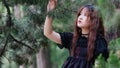 Portrait of beautiful Asian woman posing in summer forest, Chinese girl in vintage black dress looking at trees with blur nature Royalty Free Stock Photo