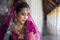 Portrait of a beautiful Asian woman in a purple sari sitting and looking at down in a temple pavilion while traveling in Asia Royalty Free Stock Photo