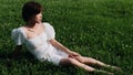 Portrait of beautiful Asian woman sitting on meadows in summer forest, Chinese girl in white dress sleeping with eyes closed Royalty Free Stock Photo