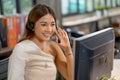 Portrait of beautiful Asian woman smile in front of monitor and work as operator or call center with happiness in office Royalty Free Stock Photo