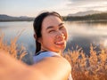 Portrait of beautiful asian woman smiling and looking to camera at sunset lakeside