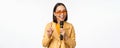 Portrait of beautiful asian woman in sunglasses, stylish girl singing, giving speech with microphone, holding mic and Royalty Free Stock Photo