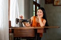 Portrait of beautiful Asian woman with traditional cloth and sit near old sewing machine and look at camera with smiling Royalty Free Stock Photo