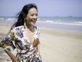 Beautiful asian woman wearing bohemian clothing style with pineapple earrings smiling with freshness face walking on the beach Royalty Free Stock Photo