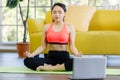 Portrait of beautiful Asian woman wearing a sport suit sitting on a yoga mat closing eye do meditation after yoga exercise with Royalty Free Stock Photo