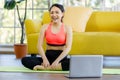 Portrait of beautiful Asian woman wearing a sport suit sitting on a yoga mat smiling happily after finnish exercise in a living Royalty Free Stock Photo