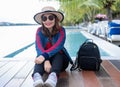 Portrait of a beautiful Asian woman wearing a straw hat and sunglasses smiling at the summer waterfront on vacation