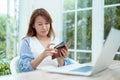 Portrait of a beautiful Asian woman in a white shirt sitting in front of a computer, taking out her credit card from her purse, Royalty Free Stock Photo