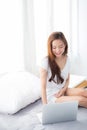 Portrait of beautiful asian young woman setting on bed using laptop computer at bedroom for leisure and relax. Royalty Free Stock Photo