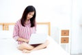 Portrait of beautiful asian young woman setting on bed using laptop computer at bedroom for leisure and relax. Royalty Free Stock Photo