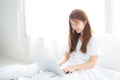 Portrait of beautiful asian young woman setting on bed using laptop computer at bedroom for leisure and relax. Royalty Free Stock Photo