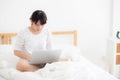 Portrait of beautiful asian young woman sitting on bed using laptop computer at bedroom for leisure and relax Royalty Free Stock Photo