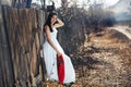 Portrait of a Beautiful black haired girl in a white vintage dress standing near wood fence.Young woman model posing in a russian Royalty Free Stock Photo