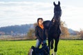 Portrait of beautiful black horse  with his owner and rider  posing in green grass meadow. autumn season Royalty Free Stock Photo