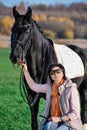 Portrait of beautiful black horse  with his owner and rider  posing in green grass meadow. autumn season Royalty Free Stock Photo