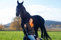 Portrait of beautiful black horse  with his owner and rider  posing in green grass meadow. autumn season Royalty Free Stock Photo