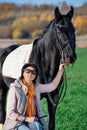 Portrait of beautiful black horse  with his owner and rider  posing in green grass meadow. autumn season Royalty Free Stock Photo