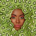 Portrait of a beautiful black woman against the background of sliced kiwi fruit Royalty Free Stock Photo