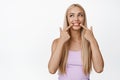 Portrait of beautiful blond girl brag with her white healthy smile, pointing finger at teeth, smiling and looking aside Royalty Free Stock Photo