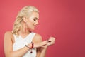 Portrait of beautiful blond hair woman looking at hand with manicured nails on colorful pink background Royalty Free Stock Photo