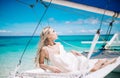 Portrait of the beautiful blond long hair bride in white dress. She lay on the blue sailboat. Blue sky and turquoise se Royalty Free Stock Photo