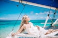 Portrait of the beautiful blond long hair bride in white dress. She lay on the blue sailboat. Royalty Free Stock Photo