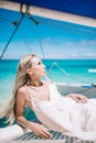 Portrait of the beautiful blond long hair bride in white dress. She lay on the blue sailboat. Royalty Free Stock Photo