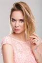 Portrait of beautiful blond sensual woman in pink cocktail dress on grey background Royalty Free Stock Photo