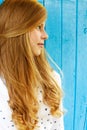 Portrait of a beautiful blond teenage girl on a blue wall