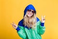 Portrait of beautiful blond woman in sunglasses and blue green hooded jacket on yellow background. hipster summer. Royalty Free Stock Photo