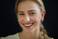 Portrait of beautiful blond young woman looking at camera and smiling on black background, close-up Royalty Free Stock Photo