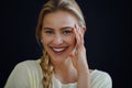 Portrait of beautiful blond young woman looking at camera and smiling on black background, close-up Royalty Free Stock Photo