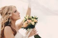 Portrait of a beautiful blonde bride with a bouquet of flowers ith wedding makeup and hairstyle. luxury bride with veil over her Royalty Free Stock Photo