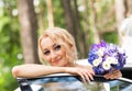 Portrait of a beautiful blonde bride with the wedding car. Royalty Free Stock Photo