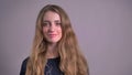 Portrait of beautiful blonde caucasian young woman watching smilingly into camera and beckoning on gray background.