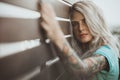 Portrait of a beautiful blonde closeup. Wearing a turquoise t-shirt. Arms tattooed. The concept of modern fashion.